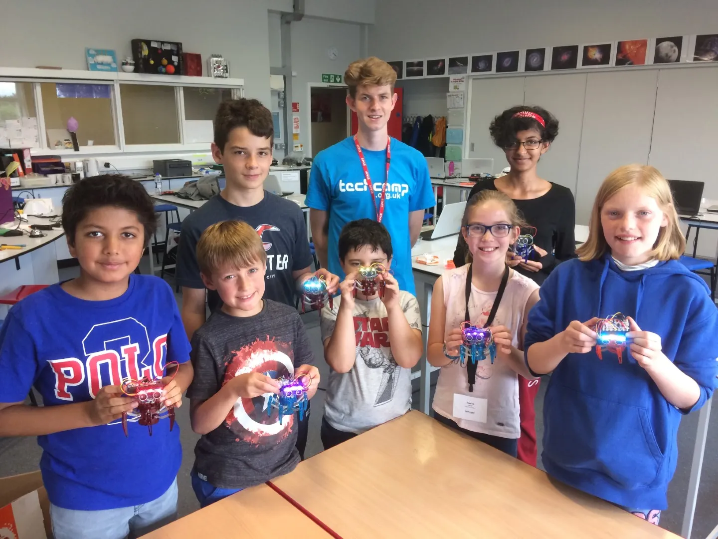Children at Tech Camp holding up the robots they have built with their tutor